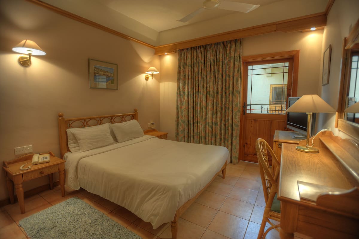 A bedroom with a bed, bedside tables, a desk, and a chair.