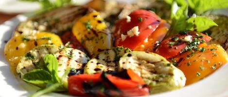 A plate of grilled chicken, tomatoes, and greens.