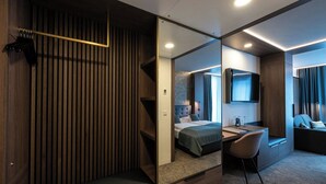 A hotel room with a bed, desk, chair, and a large mirror reflecting the room. - Stadthotel Münster (Münster)