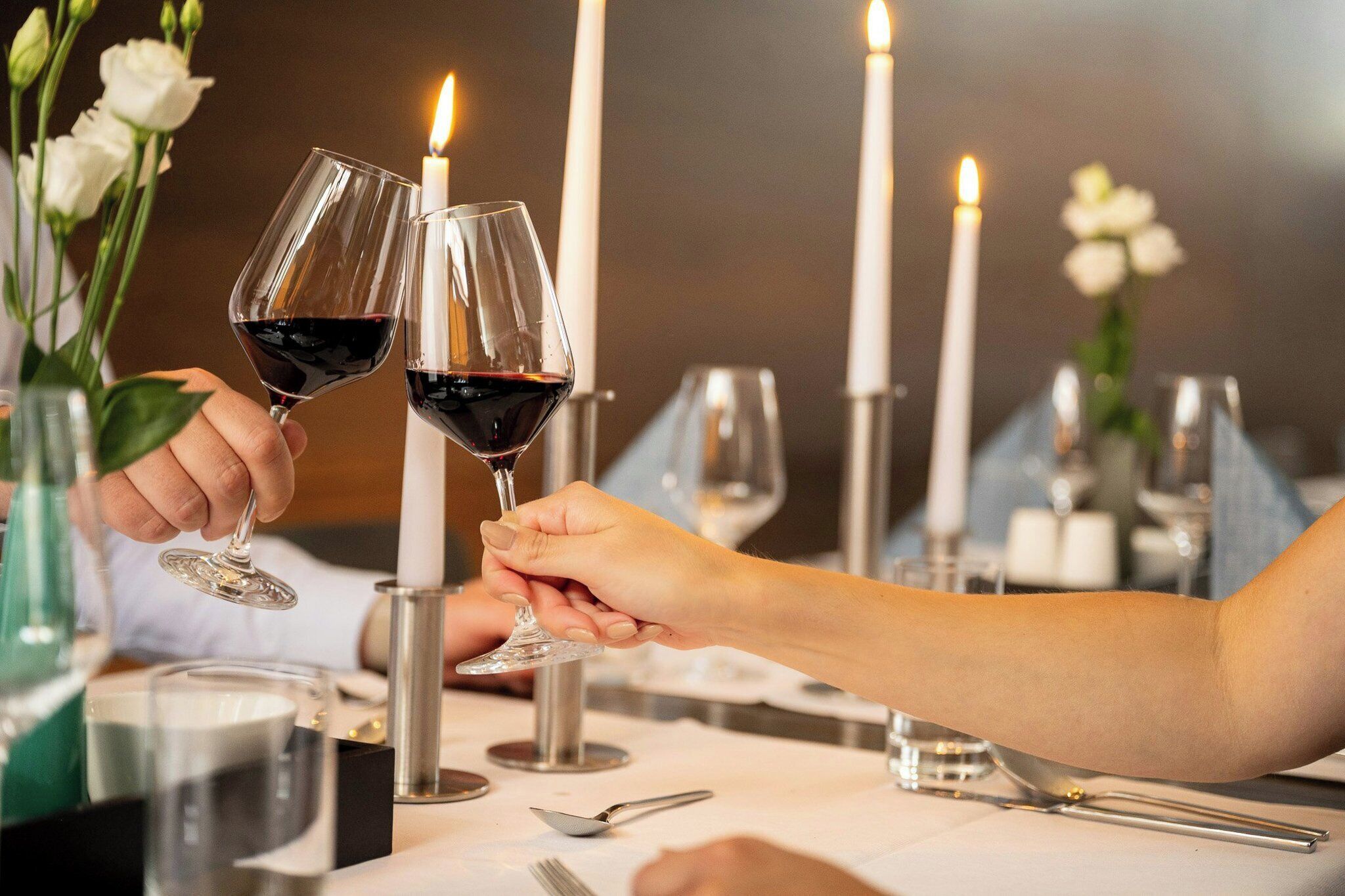A dining table with candles, wine glasses, and a vase with flowers.