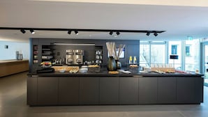 A modern kitchen area with a central island, equipped with various appliances and a buffet setup. - Stadthotel Münster (Münster)