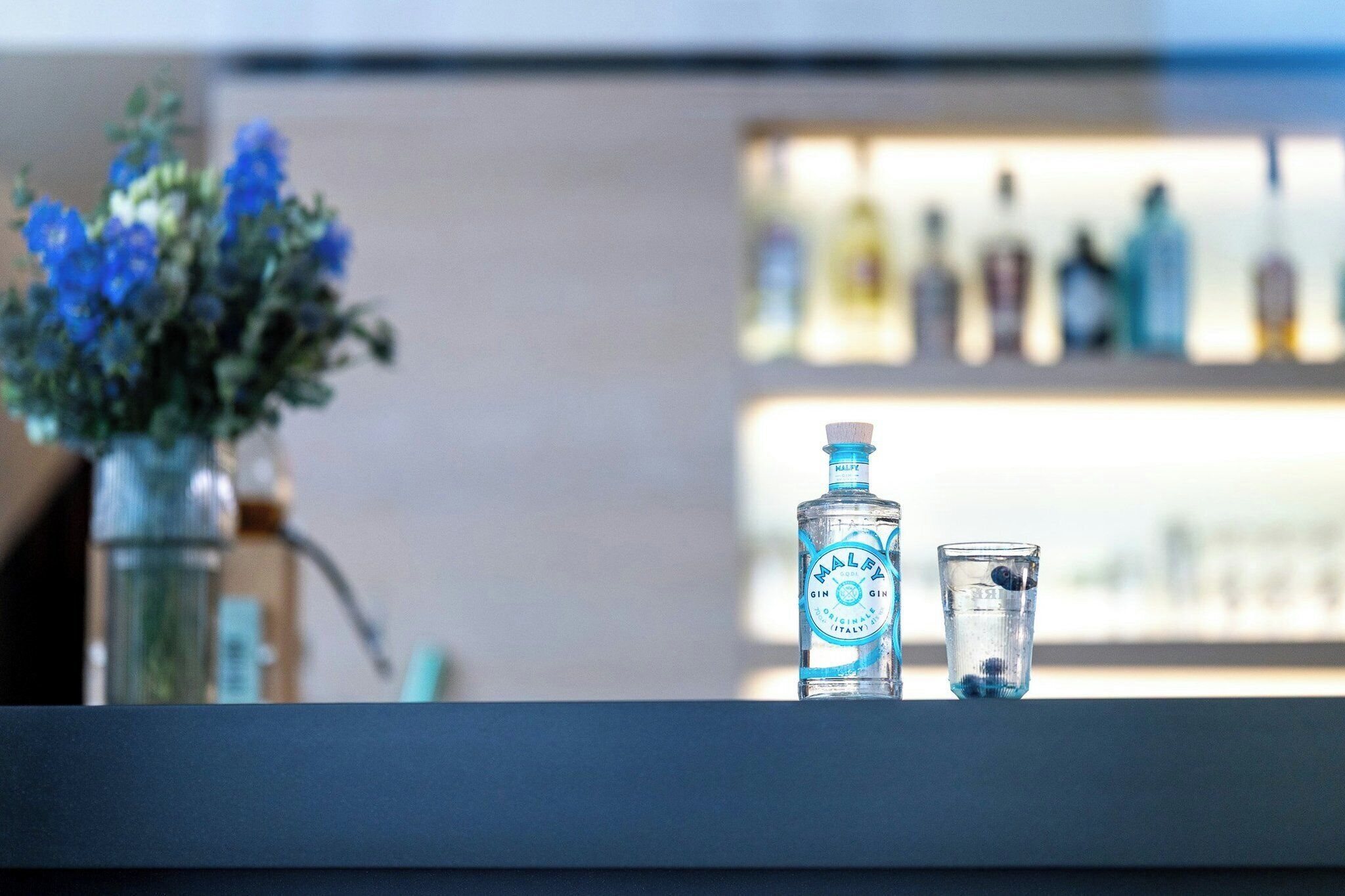 Eine Bar mit einer Flasche Gin und einem kleinen Glas.