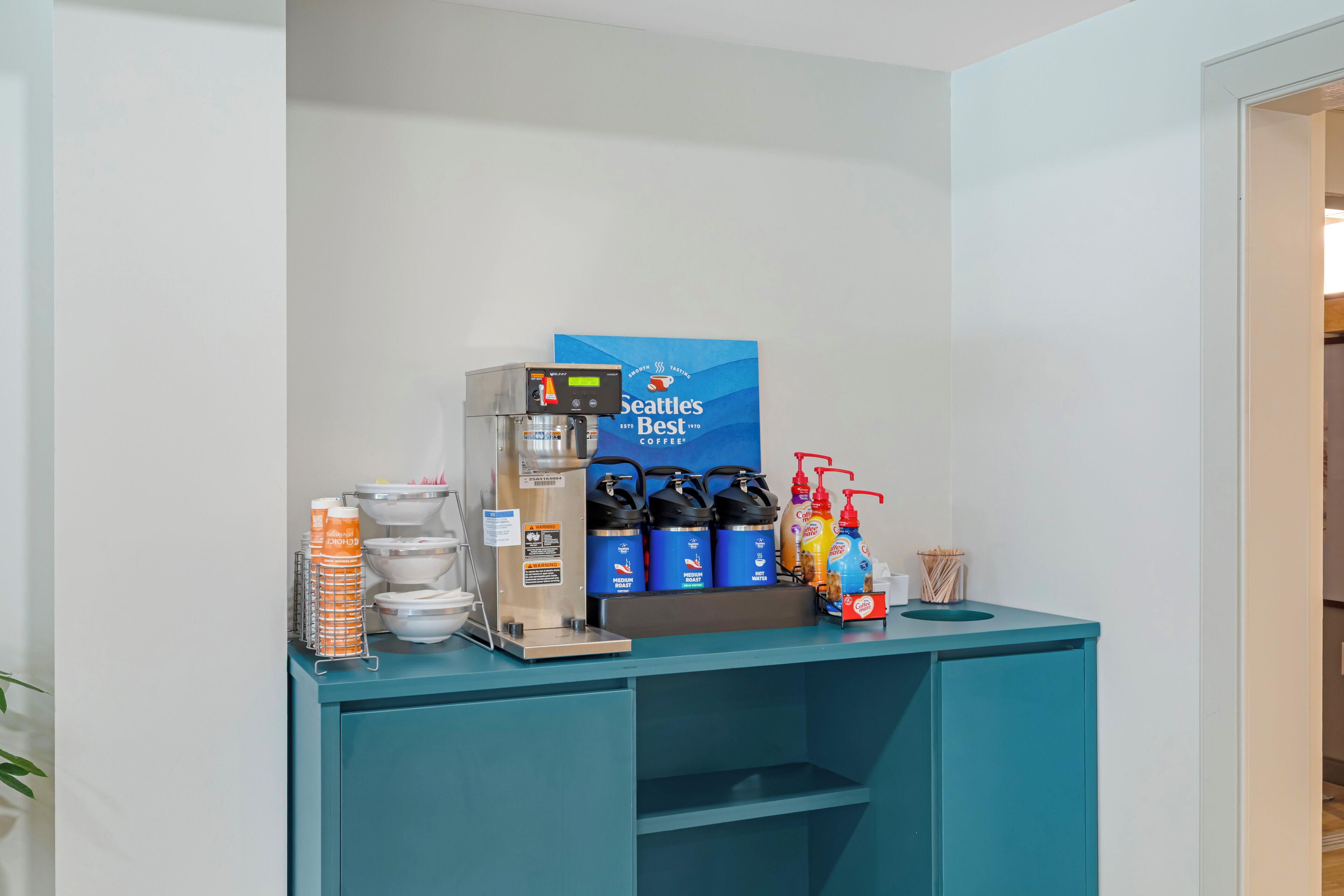 A coffee station with a Seattle's Best sign, coffee machines, and beverage dispensers.