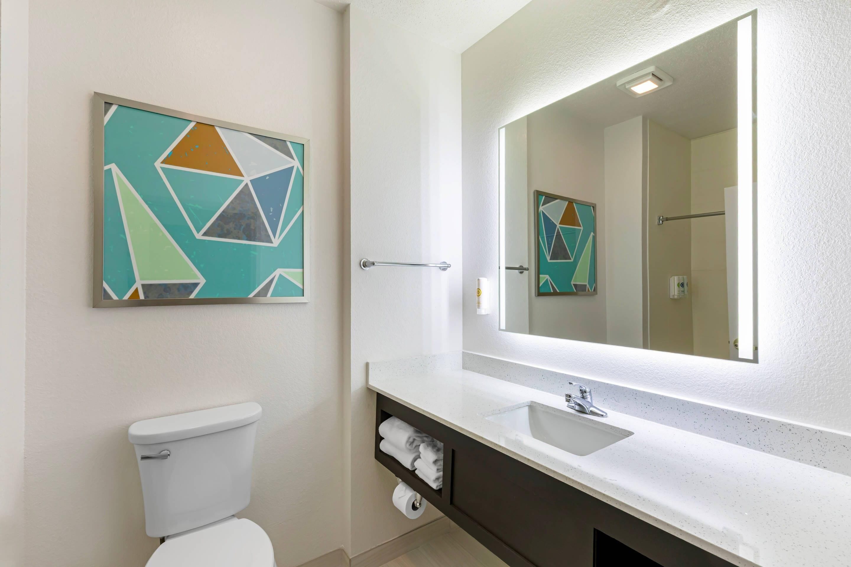 Ein Badezimmer mit Toilette, Waschbecken, Spiegel und Handtuchhalter.