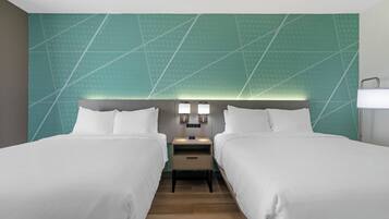 Hotelkamer met twee bedden, een nachtkastje met een lamp en een muur met een geometrisch patroon.