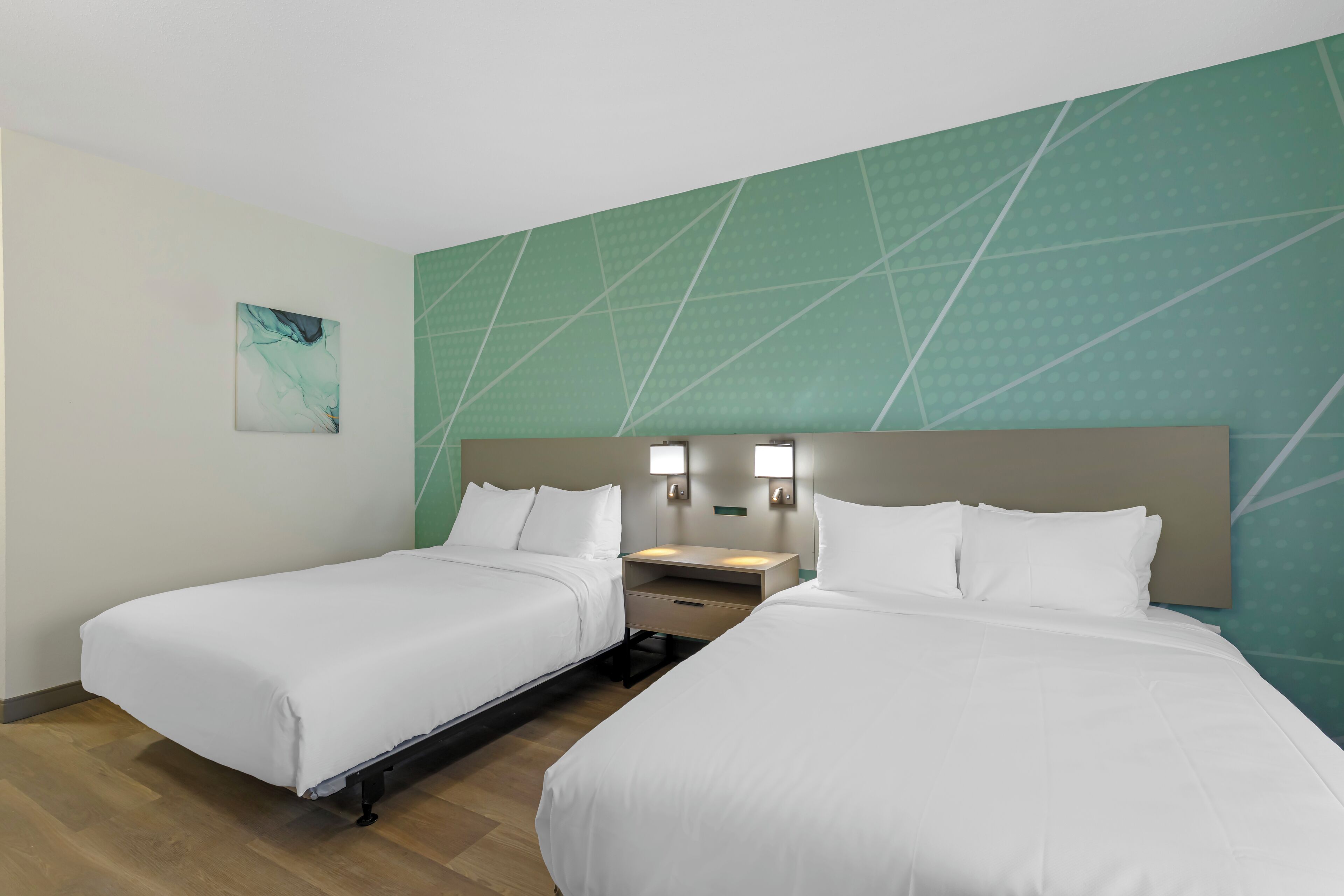Ein Hotelzimmer mit zwei Betten, einem Nachttisch und einer Wandleuchte.