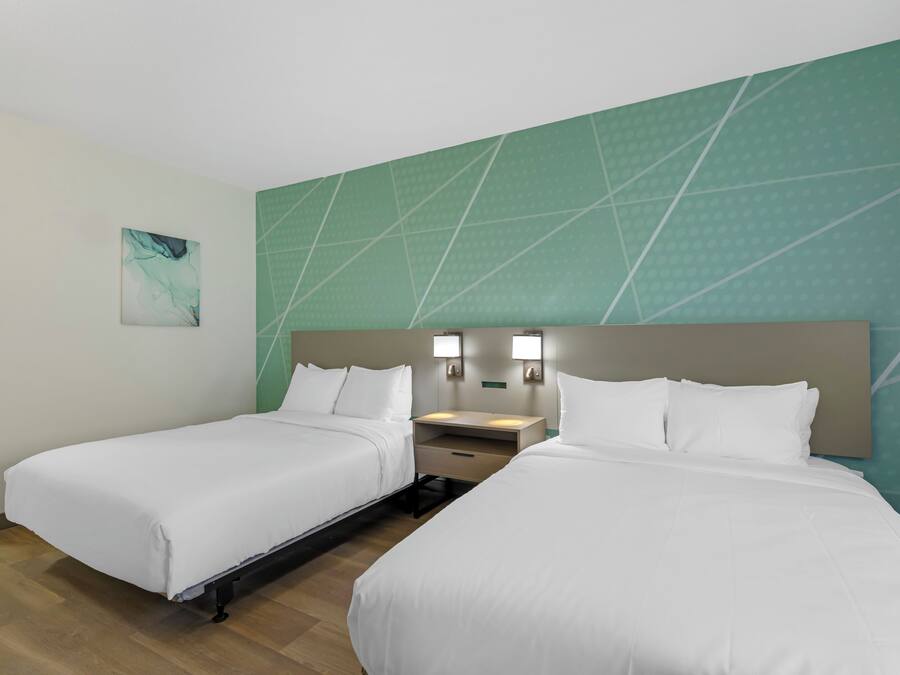 Ein Hotelzimmer mit zwei Betten, einem Nachttisch und einer Wandleuchte.