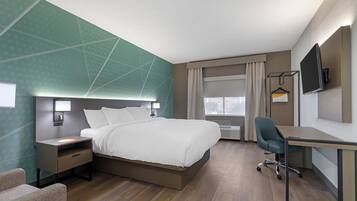 Une chambre d’hôtel moderne avec un grand lit, des tables de chevet, un bureau et une télévision.