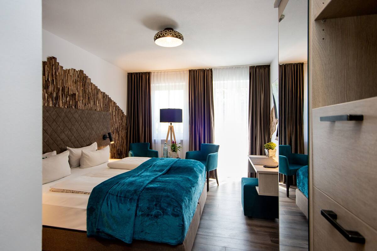A modern hotel room with a large bed, a desk, and a chair.