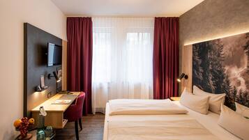 Een hotelkamer met een bed, een bureau, een stoel, een televisie en een groot schilderij aan de muur.