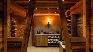 A wooden interior with a central island counter, shelves with jars, and a wall-mounted light fixture. - ARCUS HOTEL MÜNCHEN MESSE (Vaterstetten)