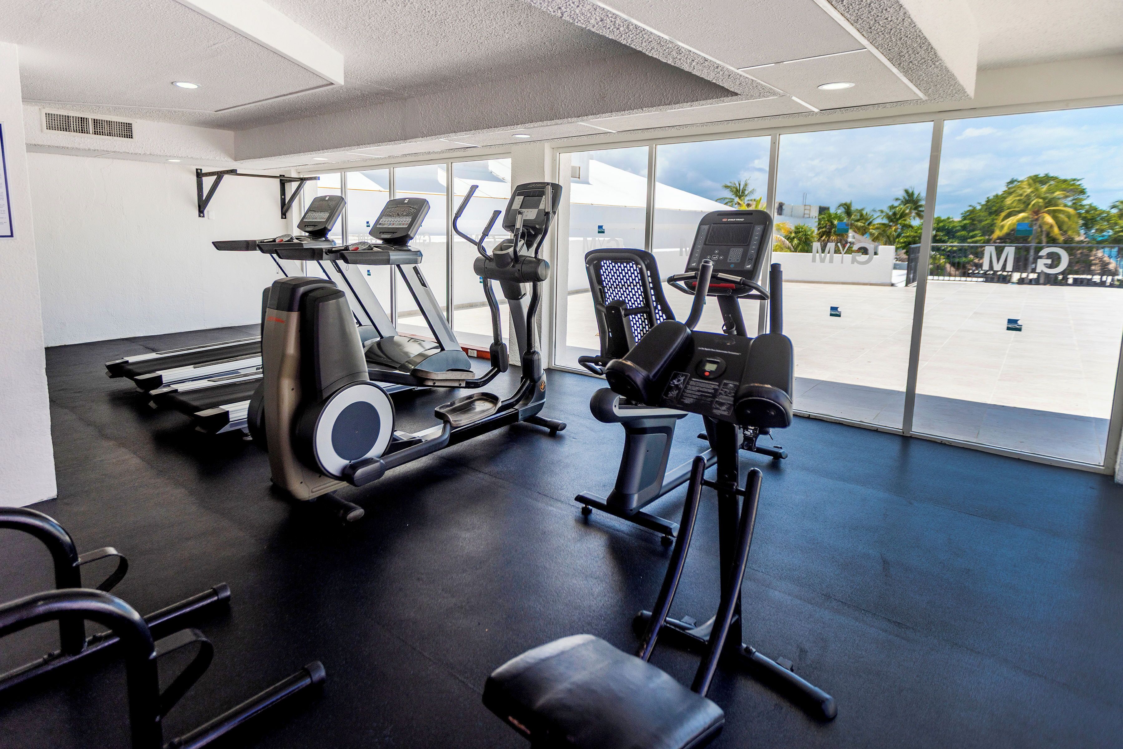 Een fitnessruimte met loopbanden, elliptische trainers en een roeiapparaat.