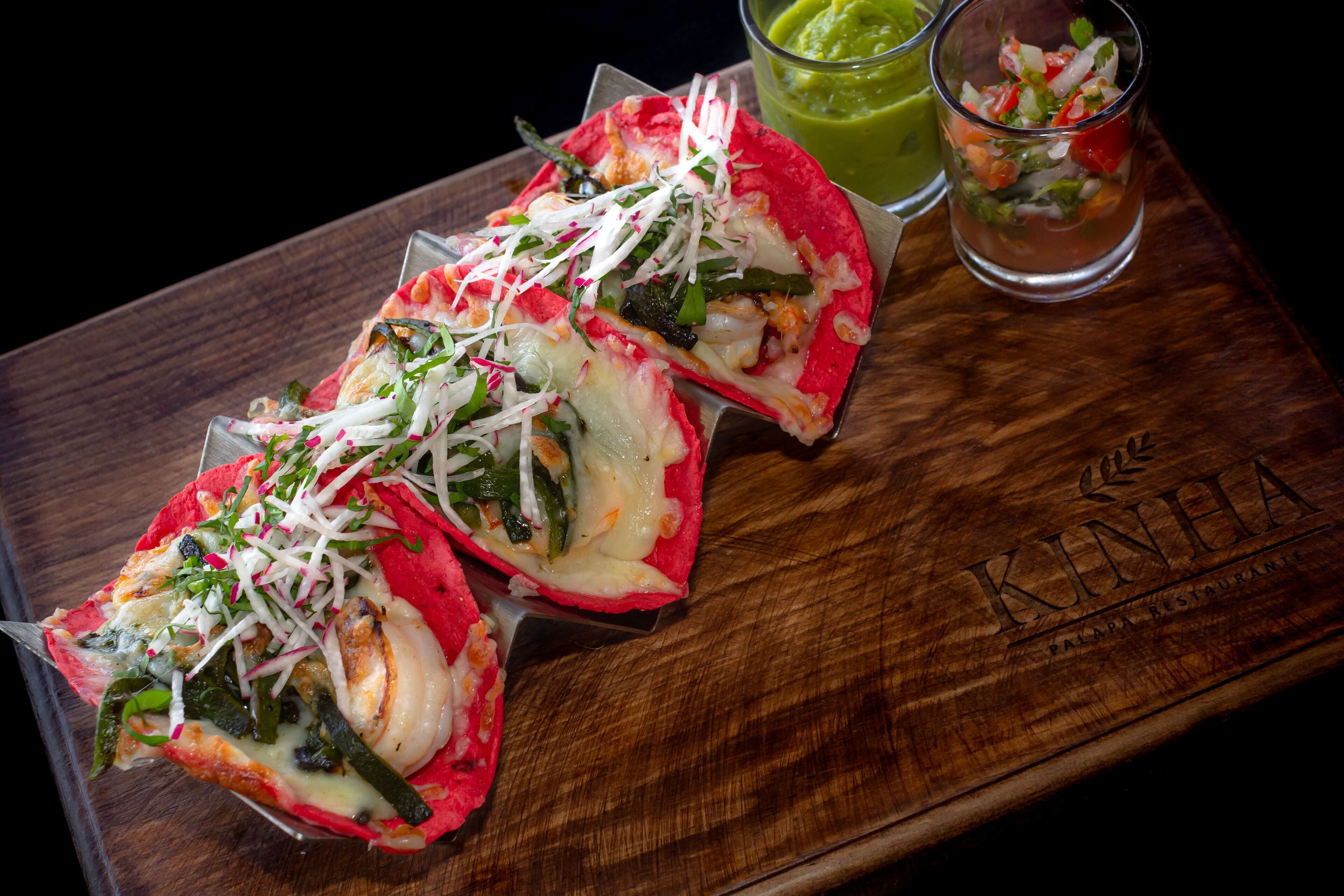 Deux tacos garnis, présentés sur une planche en bois.