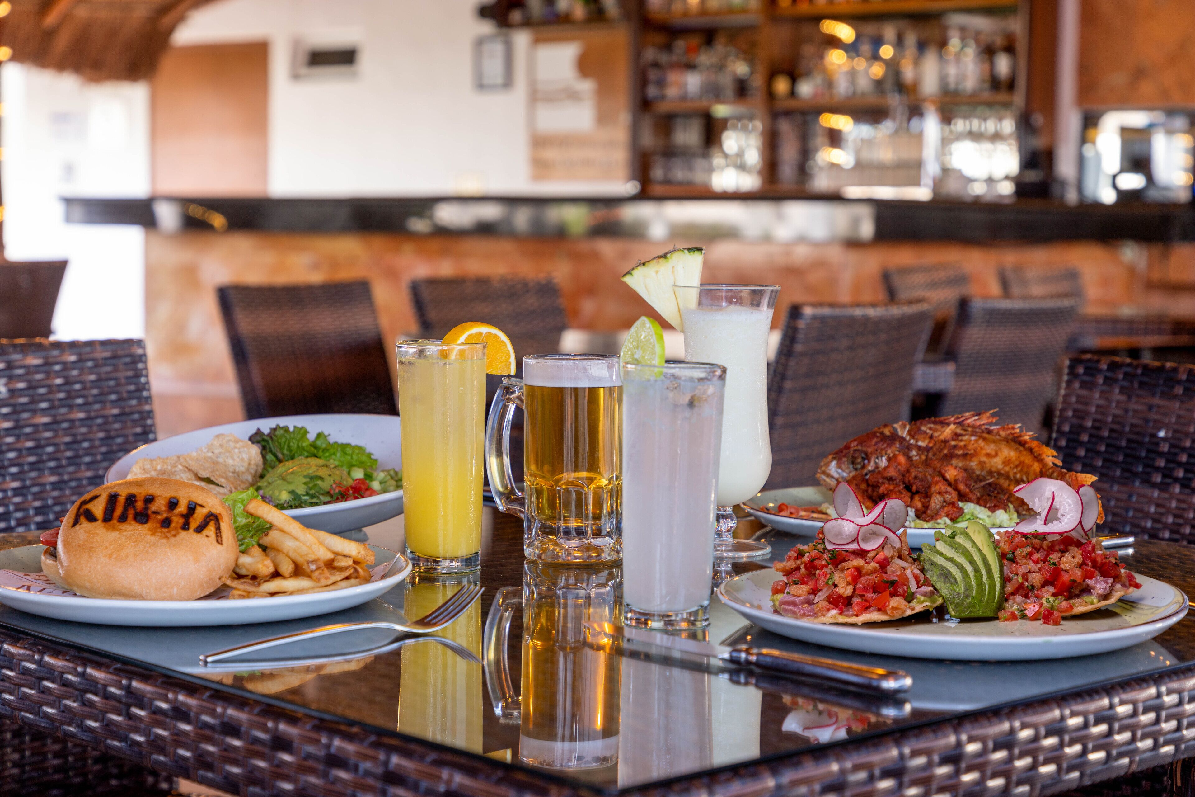 A dining table with plates of food, drinks, and a fish dish.