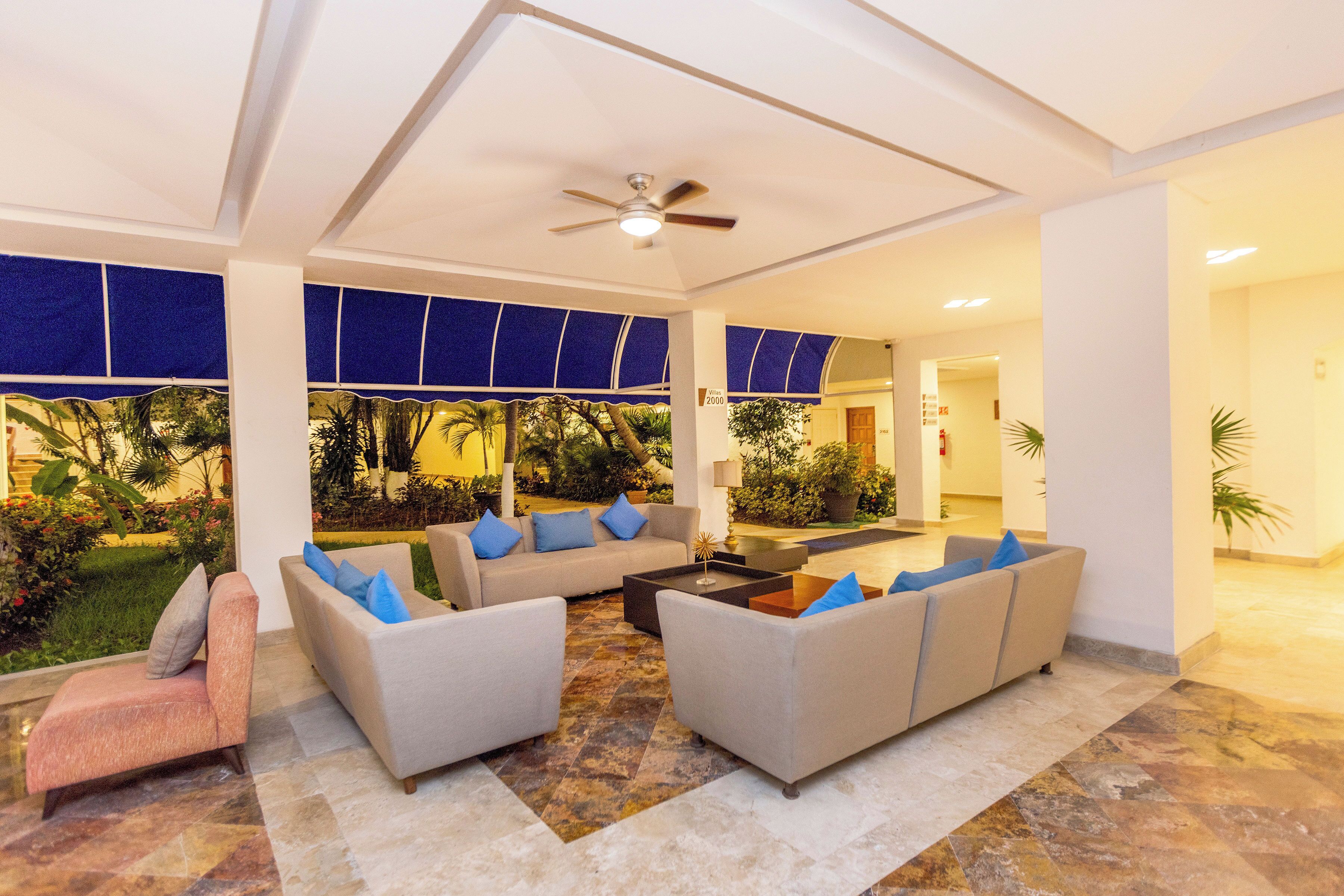 A spacious indoor area with multiple seating arrangements, a ceiling fan, and a view of the outdoors.