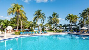 A swimming pool with blue chairs and palm trees. - Beachscape Kin ha Villas & Suites (Cancun)