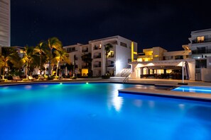 Relax by the pool surrounded by palm trees and lounge chairs.