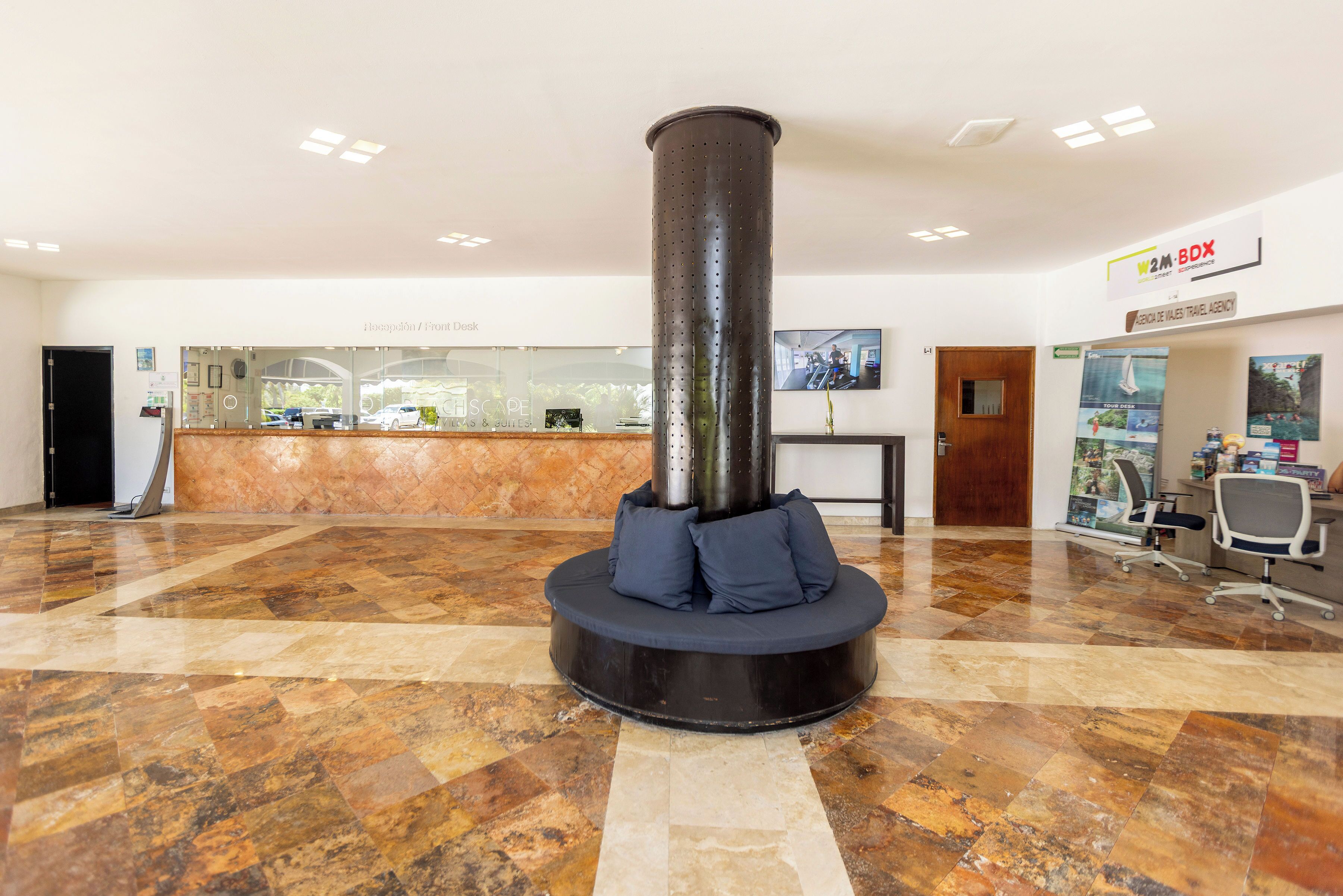 A lobby with a reception desk, a large pillar with seating, and a W2M-BOX sign.