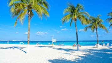 Een privéstrand, wit zand, ligstoelen aan het strand, parasols