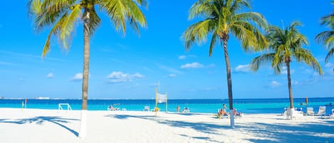 En privat strand, hvidt sand, liggestole, parasoller