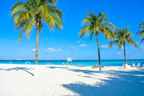 Praia particular, areia branca, espreguiçadeiras, guarda-sóis 