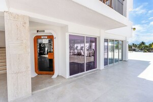 A gym with glass doors, a white exterior, and a balcony.