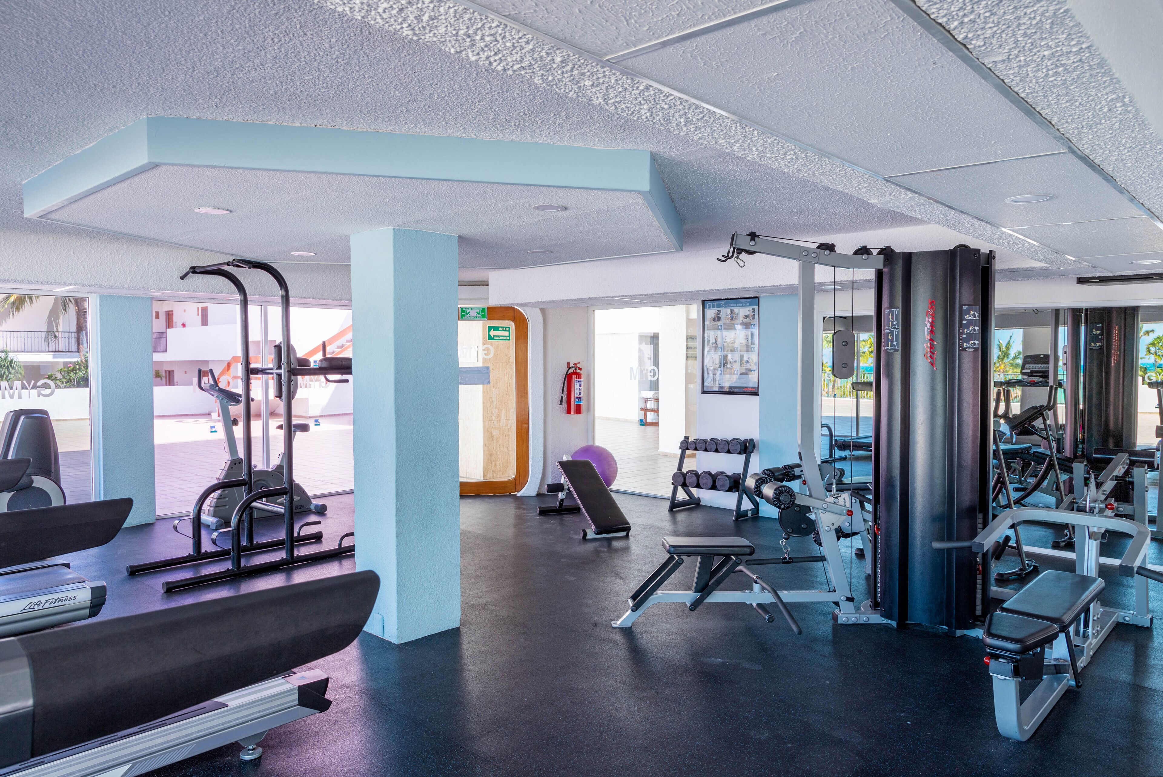 A modern gym with cardio machines, free weights, and a variety of exercise equipment.