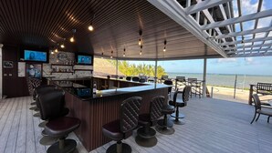 A bar area with a wooden ceiling, bar stools, a counter, and a TV screen. - Captain Morgan's Retreat (San Pedro)