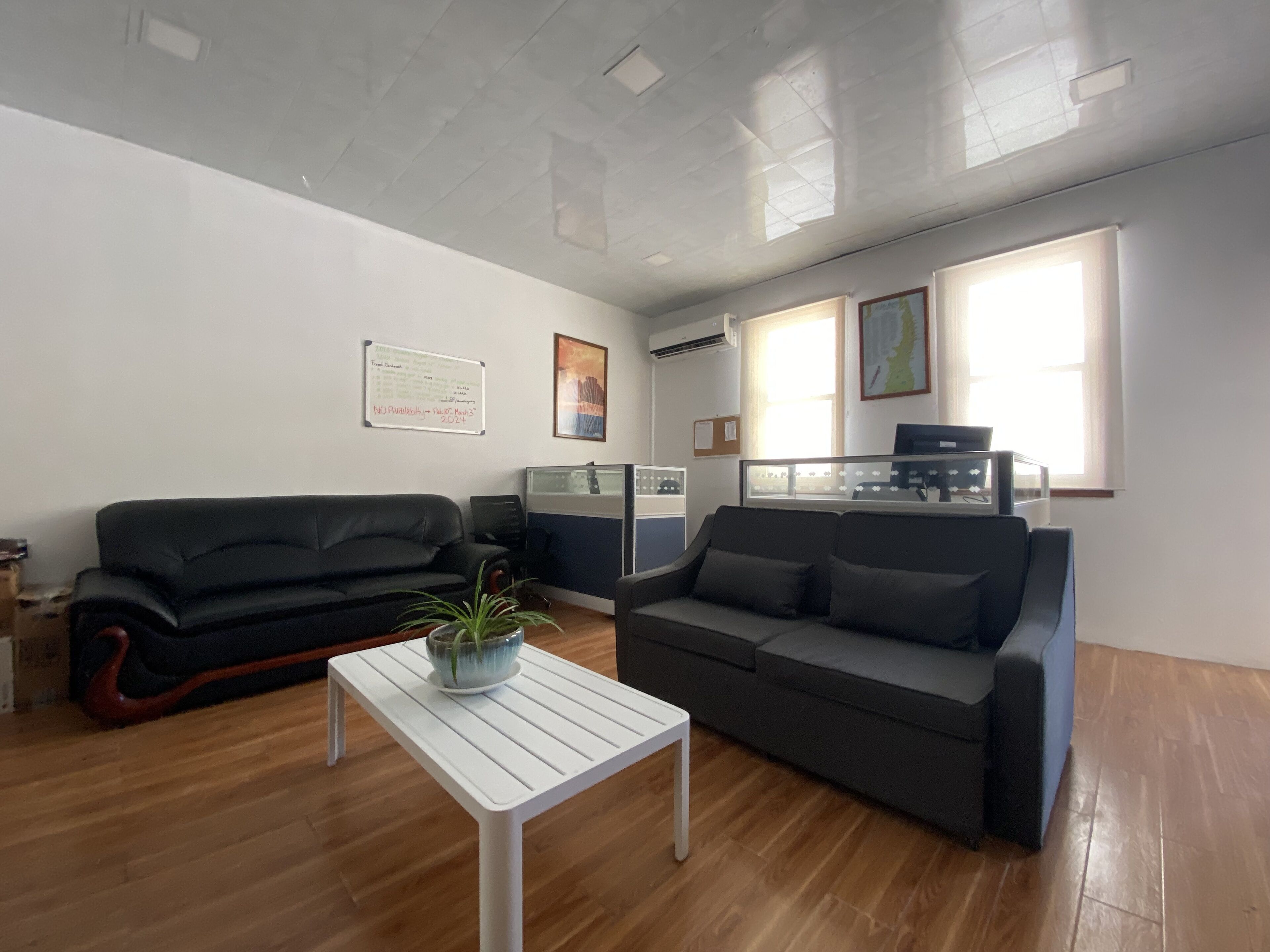 A modern living room with two sofas, a white coffee table, and a large window providing natural light.