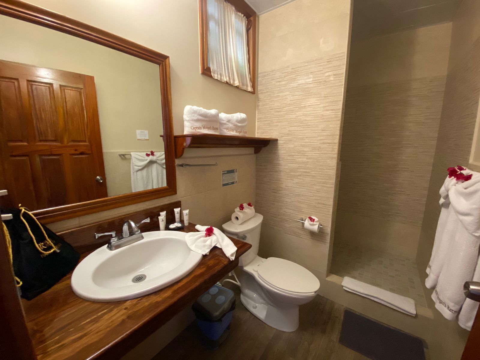 A bathroom with a wooden vanity, a sink, a mirror, a toilet, and a shower area.