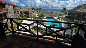 A resort with a pool, thatched-roof structures, and a view of the ocean. - Captain Morgan's Retreat (San Pedro)