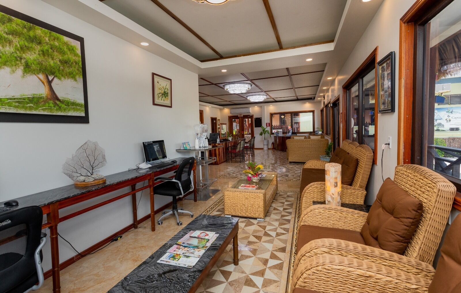 Een hotellobby met een receptiebalie, een zithoek en uitzicht naar buiten.