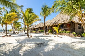 A beachside resort with thatched-roof huts, palm trees, and a sandy beach. - Captain Morgan's Retreat (San Pedro)