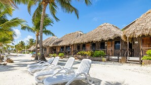 A beachside resort with thatched-roof huts, white lounge chairs, and palm trees. - Captain Morgan's Retreat (San Pedro)