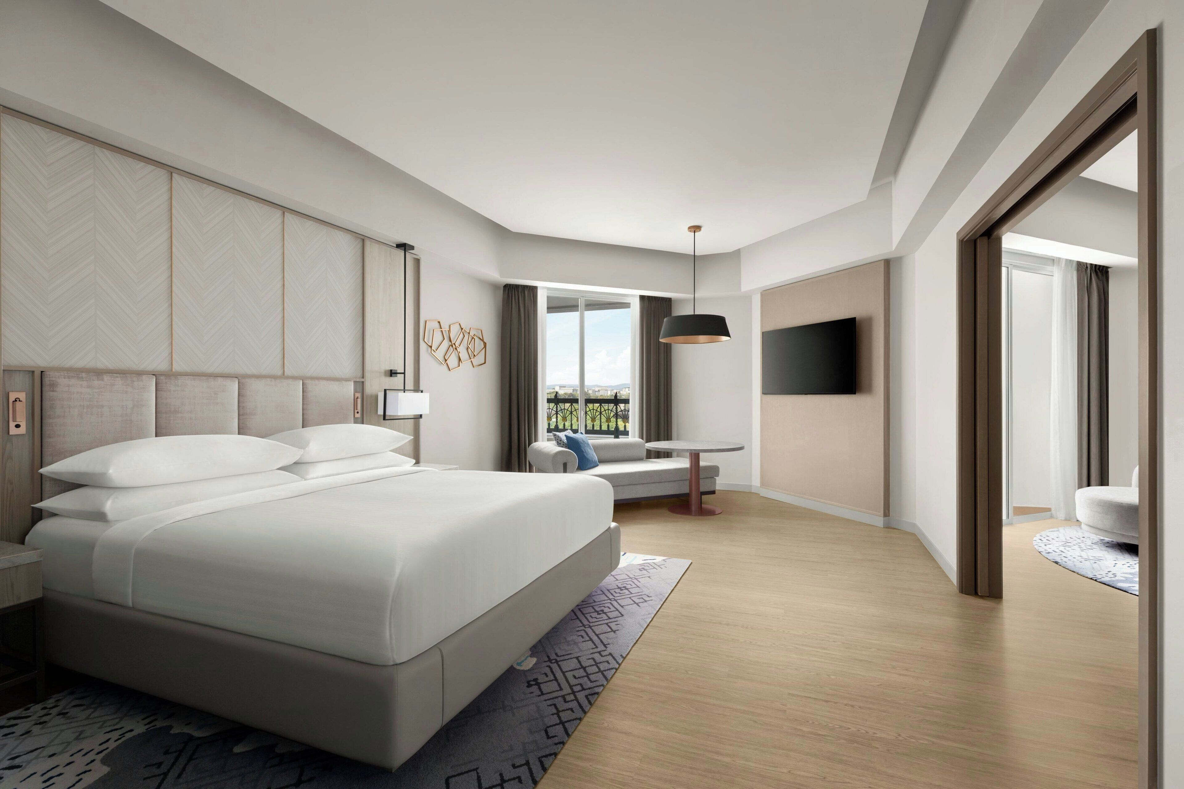 A modern hotel room with a large bed, a desk, and a TV.