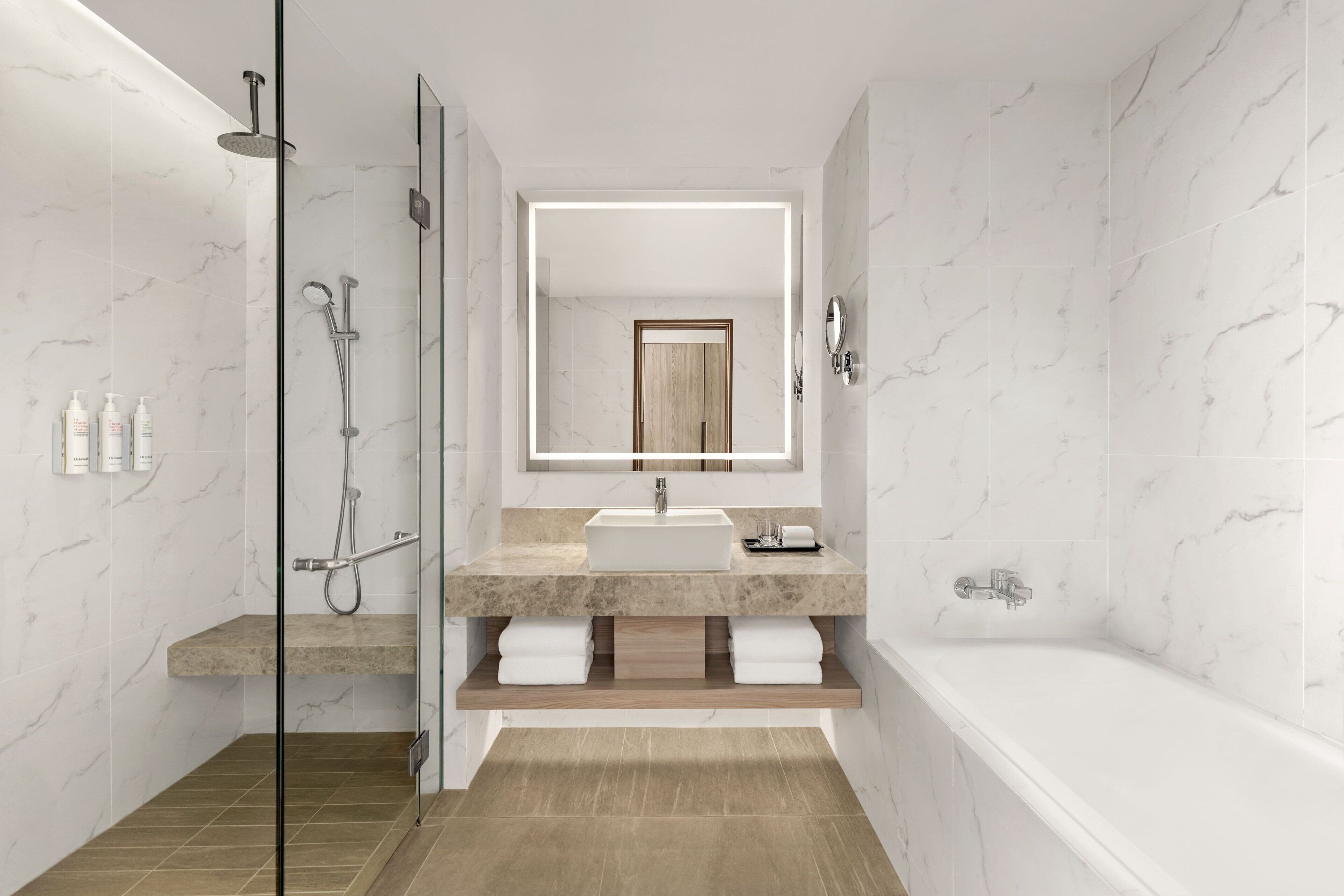 Un baño moderno con ducha de vidrio, tocador con espejo grande y bañera.