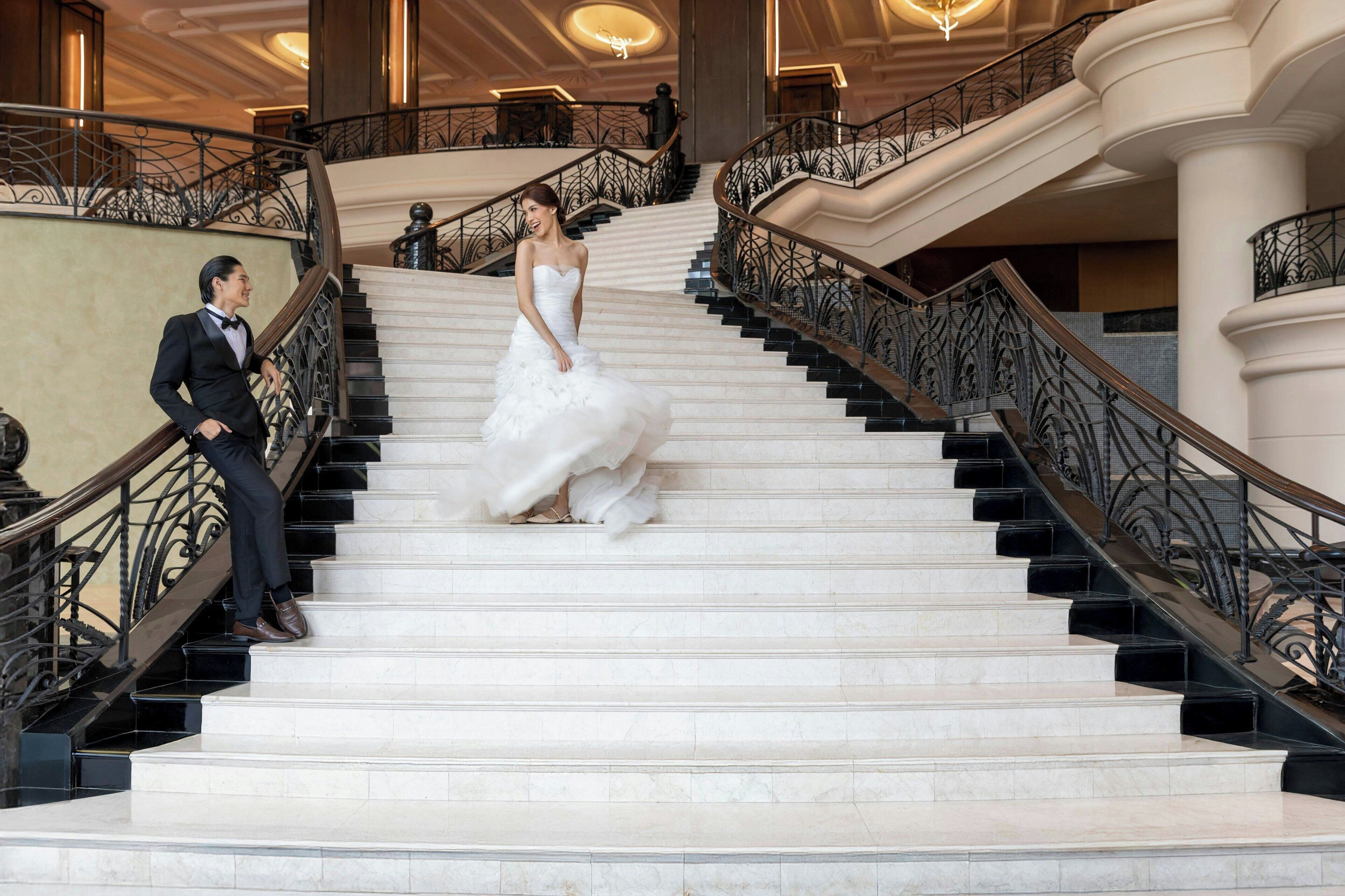 Un magnifique escalier avec des marches en marbre et des rampes noires richement décorées.