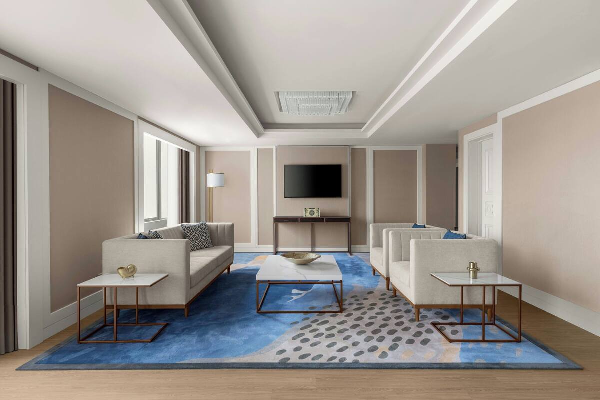 Una sala de estar moderna con una televisión de pantalla plana, dos sofás, una mesa de centro y una alfombra estampada.