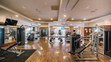 A spacious gym with various exercise equipment, a large mirror, and a television.