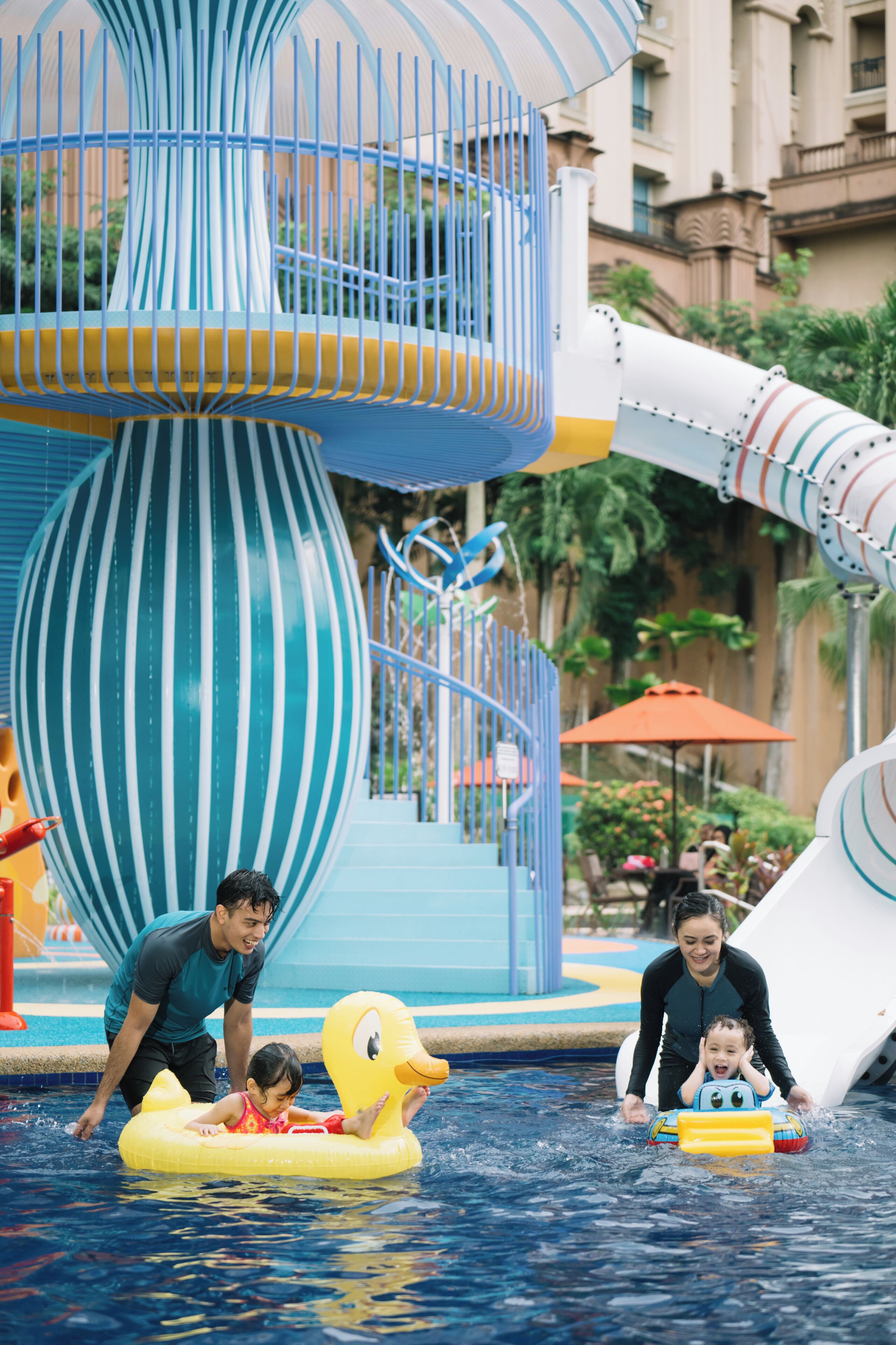 Um parque aquático com um grande escorregador espiral azul e branco, um flutuador de pato e um toboágua.