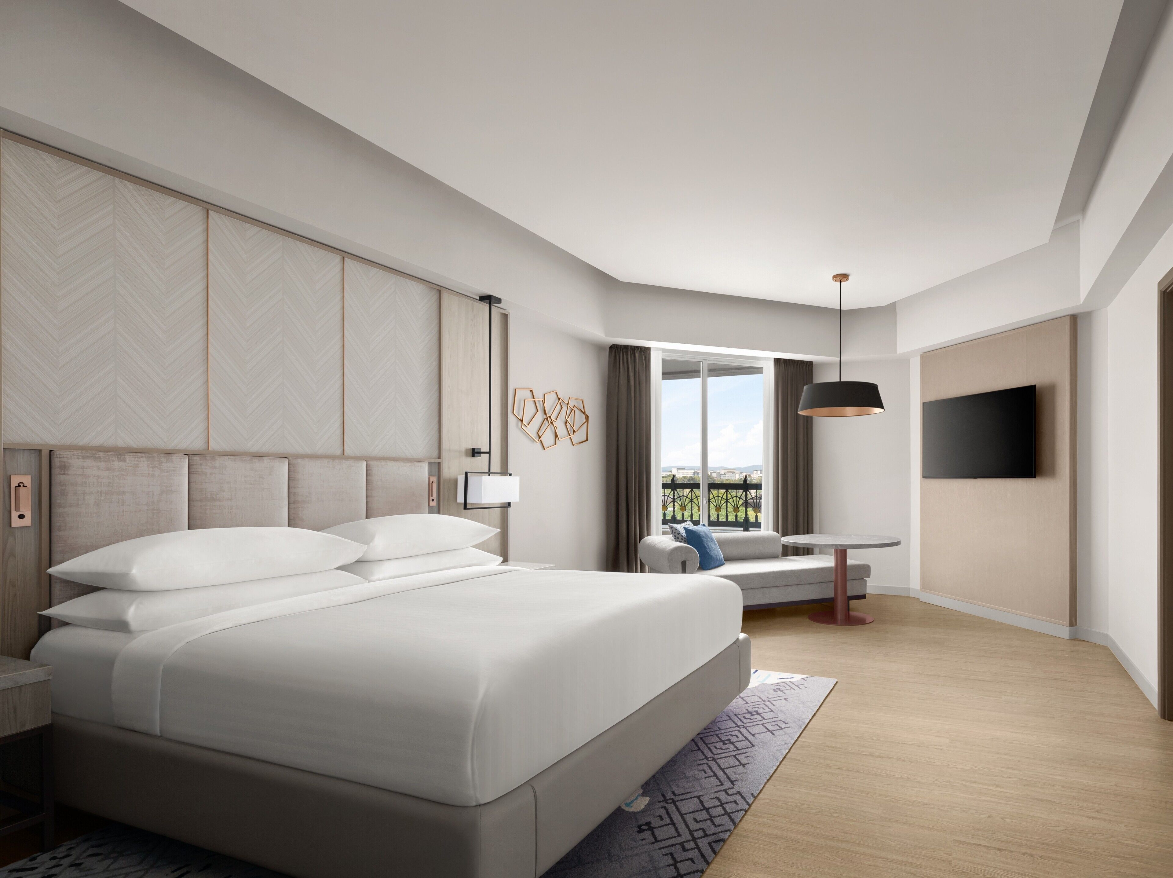 Een moderne hotelkamer met een groot bed, een bureau met stoel, een aan de muur bevestigde televisie, en een balkon met uitzicht.