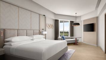 A modern hotel room with a large bed, a desk with a chair, a TV mounted on the wall, and a balcony with a view.