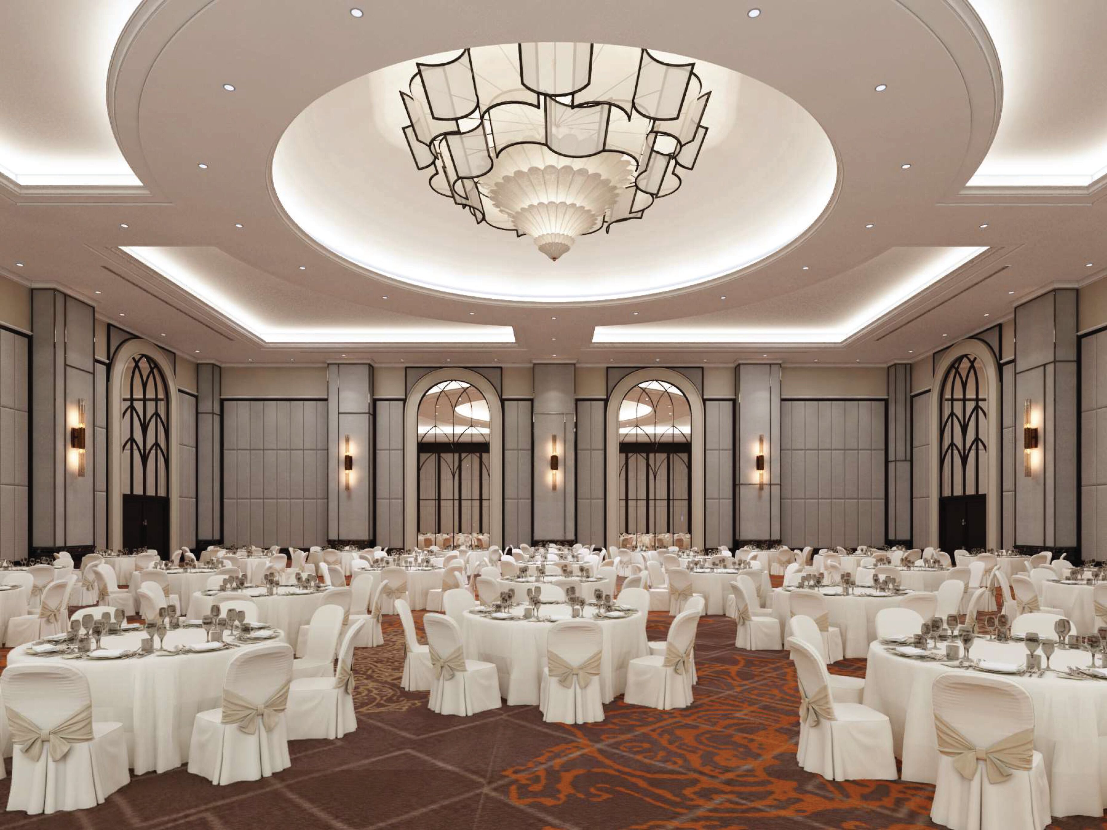 A large banquet hall with round tables, white chairs, and a central chandelier.