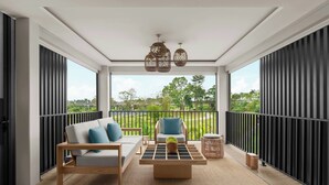 Un balcón moderno con sofá, sillón y mesa de centro, que ofrece vistas a zonas verdes y un cielo despejado.