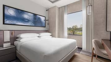 A modern hotel room with a large bed, a desk, and a view of the outdoors.