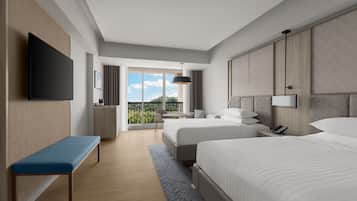 Una habitación de hotel moderna con una cama grande, una cama más pequeña, un banco, un escritorio y un televisor.