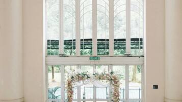 A wedding ceremony setup with a white altar, floral decorations, and a red aisle rug.