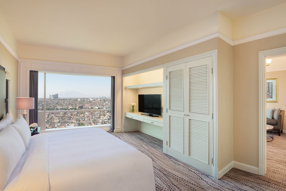 A hotel room with a large bed, a television, a desk, and a wardrobe.