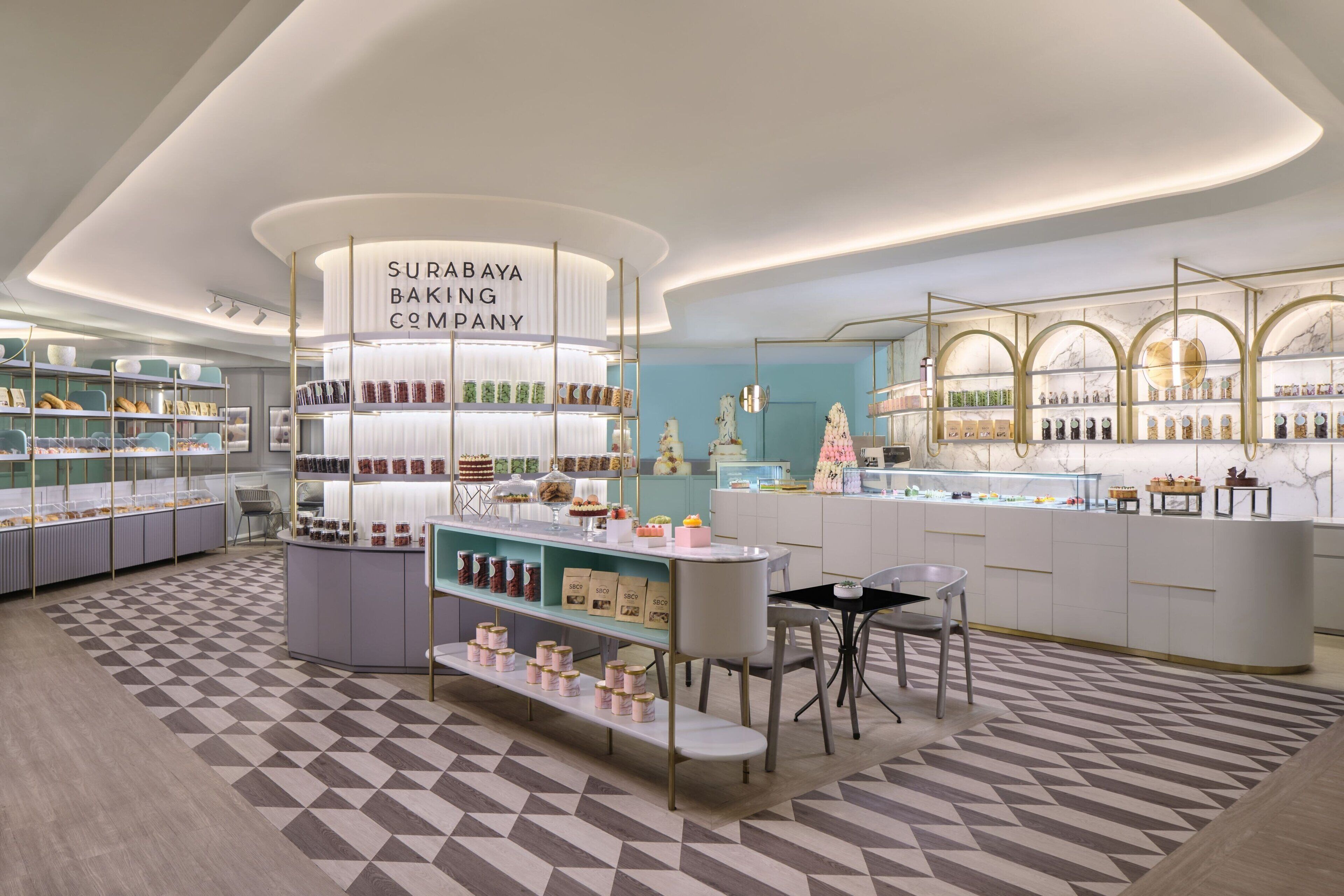 A modern bakery with a central display, shelves with baked goods, and a patterned floor.