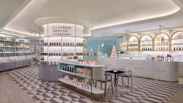 A modern bakery with a central display, shelves with baked goods, and a patterned floor.
